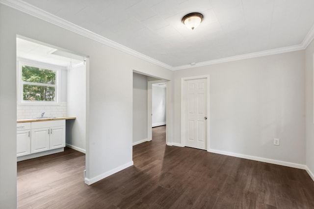 unfurnished room with sink, ornamental molding, and dark wood-type flooring