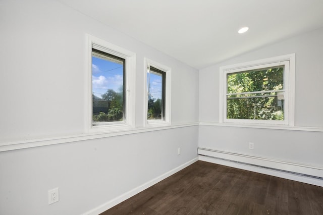 empty room featuring a healthy amount of sunlight, lofted ceiling, dark wood-type flooring, and a baseboard heating unit