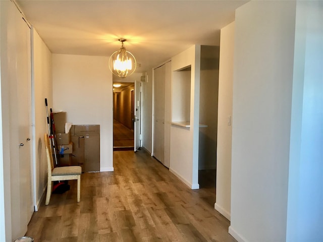 corridor with an inviting chandelier and light hardwood / wood-style flooring