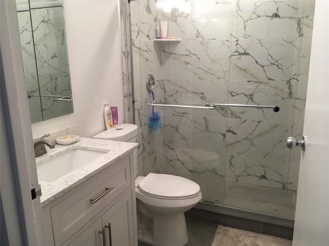 bathroom featuring toilet, vanity, and a shower with door