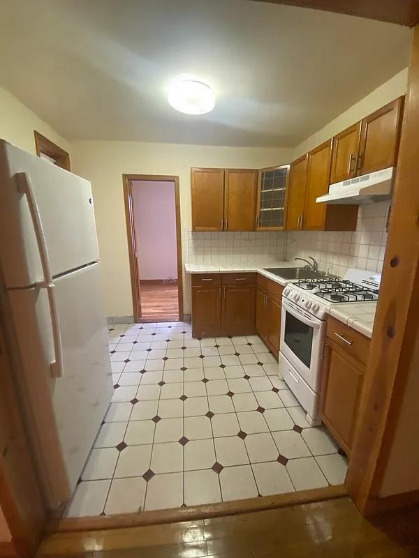 kitchen with sink, white appliances, and backsplash