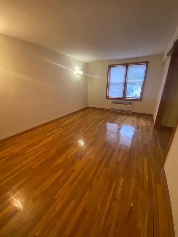 unfurnished room with radiator heating unit and hardwood / wood-style floors