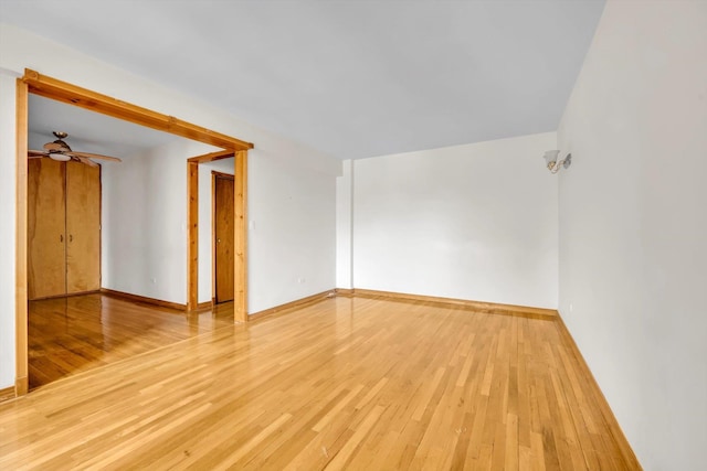 spare room with light wood-type flooring, ceiling fan, and baseboards