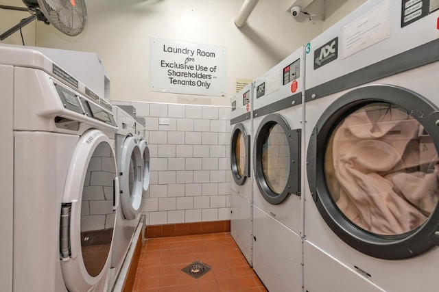 community laundry room with tile walls, washing machine and clothes dryer, and tile patterned floors