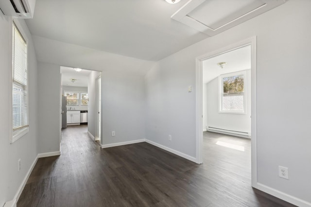 spare room with dark wood-type flooring, vaulted ceiling, a wall mounted AC, and a baseboard heating unit