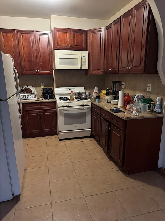 kitchen featuring light stone countertops, white appliances, and light tile patterned floors