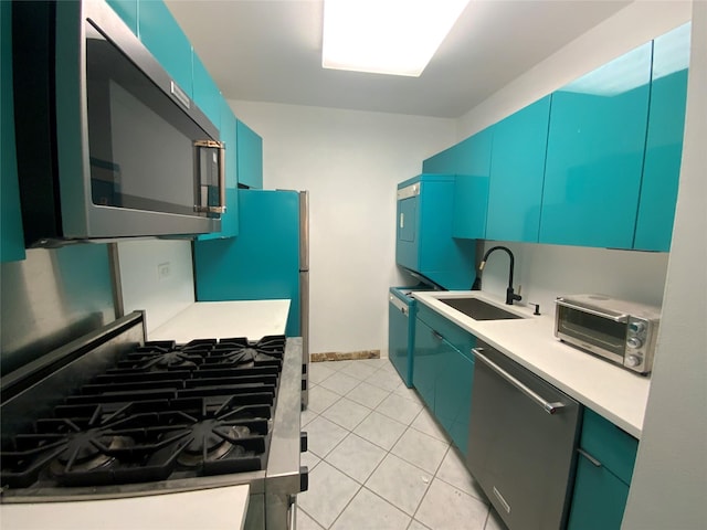 kitchen with stainless steel appliances, light tile patterned flooring, blue cabinetry, and sink