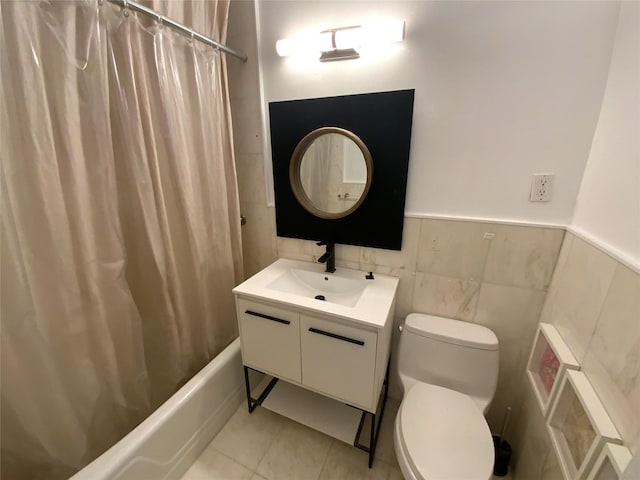 full bathroom with shower / tub combo, tile patterned flooring, toilet, vanity, and tile walls