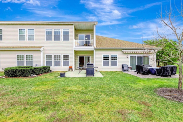 rear view of house with a balcony, a yard, and a patio