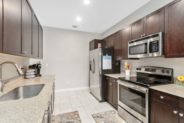 kitchen featuring light stone countertops, light tile patterned floors, appliances with stainless steel finishes, and sink