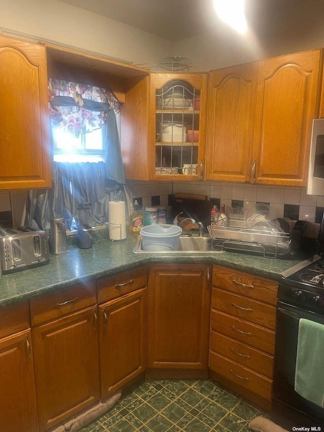 kitchen with tasteful backsplash, black range, and sink