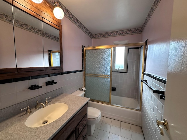 full bathroom with tile patterned floors, vanity, tile walls, enclosed tub / shower combo, and toilet