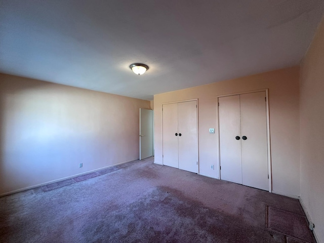 unfurnished bedroom featuring carpet and two closets