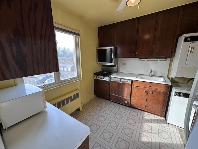 kitchen featuring stacked washer / dryer, dishwasher, radiator heating unit, and sink