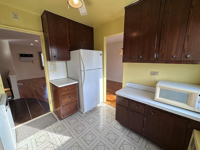 kitchen featuring dark brown cabinetry and white appliances