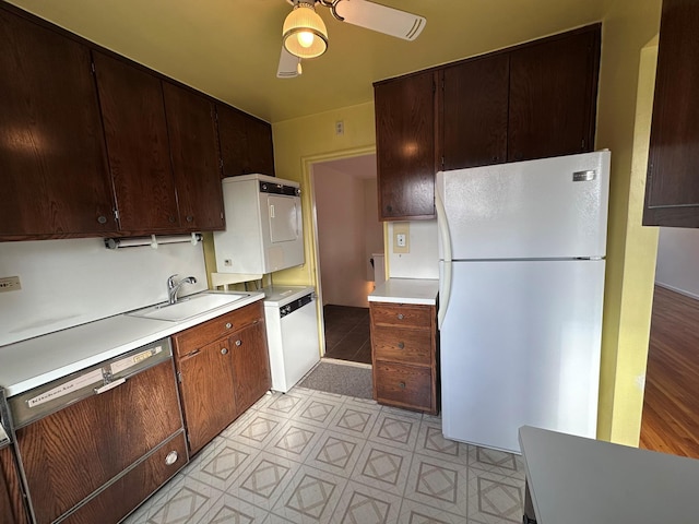 kitchen with ceiling fan, sink, white refrigerator, stacked washer and clothes dryer, and black dishwasher