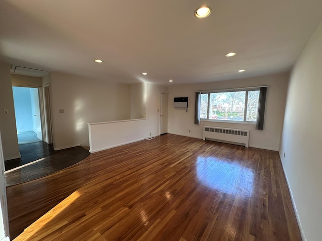 unfurnished living room featuring dark hardwood / wood-style flooring, a wall unit AC, and radiator