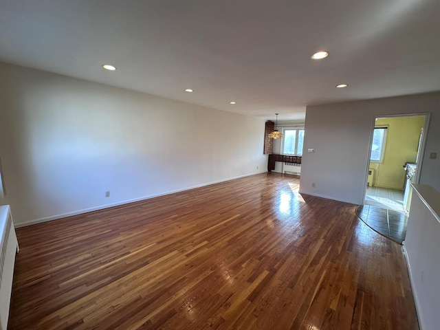 unfurnished living room featuring dark hardwood / wood-style flooring and an inviting chandelier