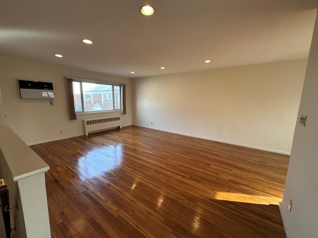 unfurnished living room featuring dark hardwood / wood-style floors, an AC wall unit, and radiator