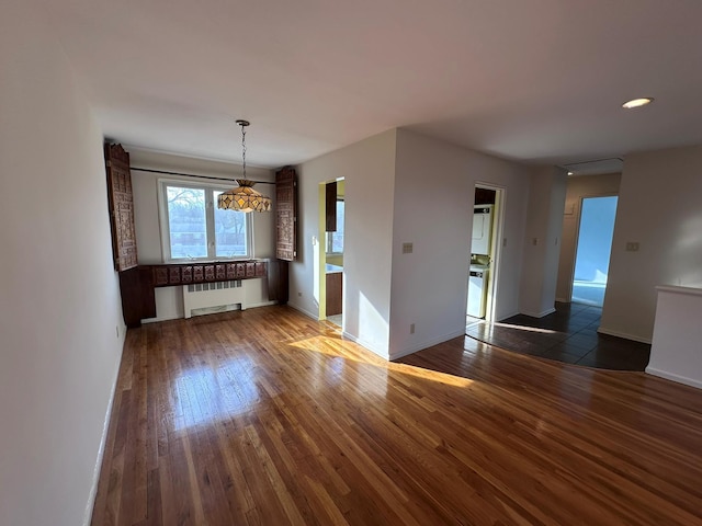 empty room featuring radiator heating unit and dark hardwood / wood-style floors