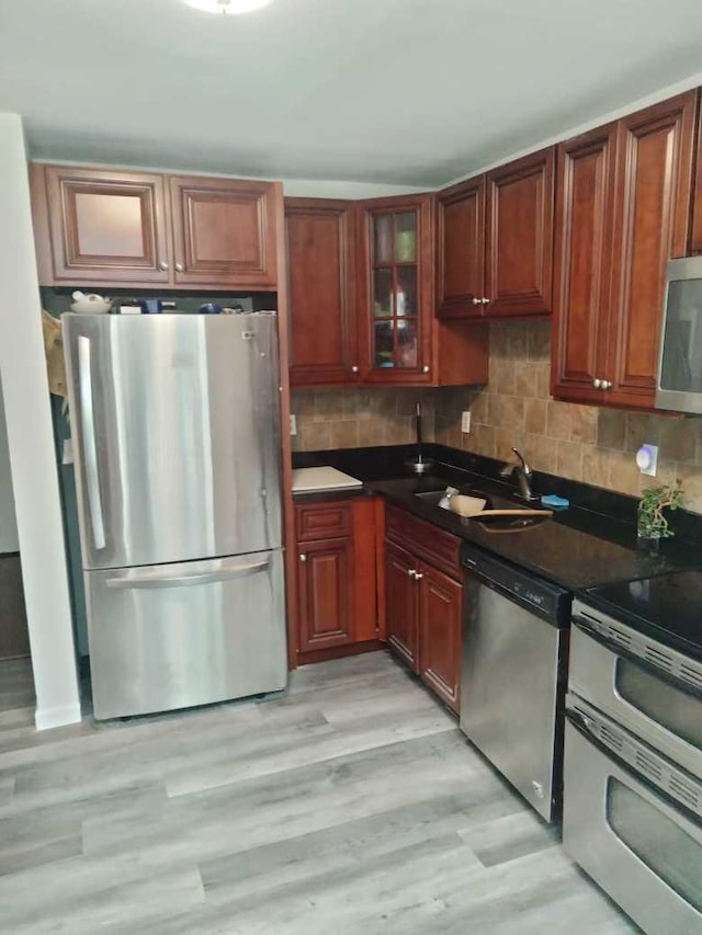 kitchen with decorative backsplash, sink, appliances with stainless steel finishes, and light hardwood / wood-style flooring