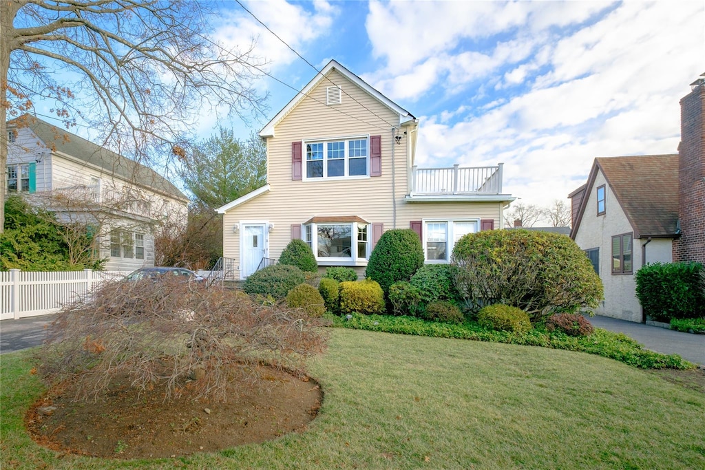 view of front of house featuring a balcony and a front lawn