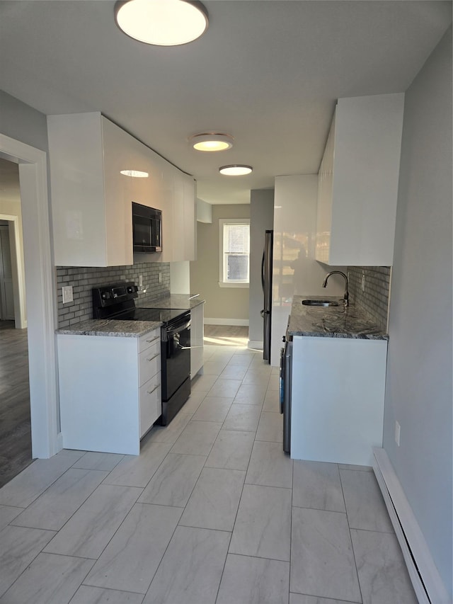 kitchen featuring dark stone counters, a baseboard heating unit, sink, black appliances, and white cabinetry