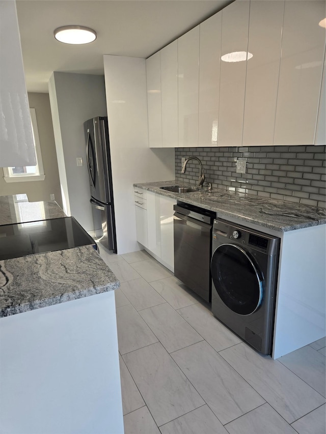 kitchen with washer / dryer, white cabinetry, and stainless steel appliances