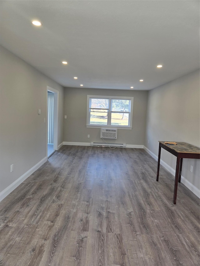 spare room with baseboard heating, dark wood-type flooring, and a wall unit AC