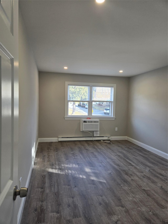 spare room featuring baseboard heating, a wall unit AC, and dark hardwood / wood-style floors