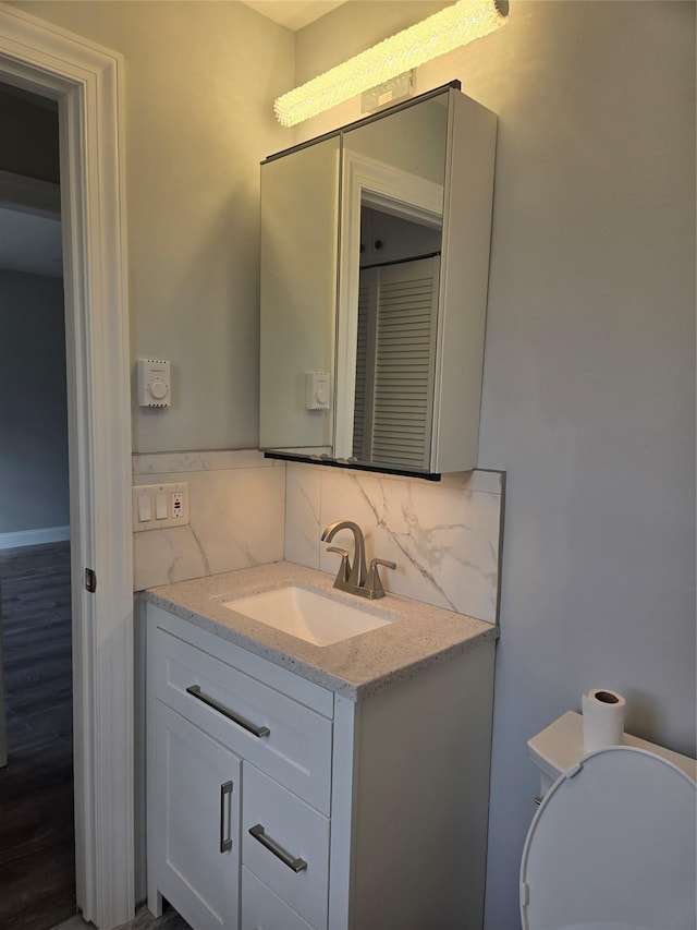 bathroom featuring decorative backsplash, toilet, wood-type flooring, and vanity