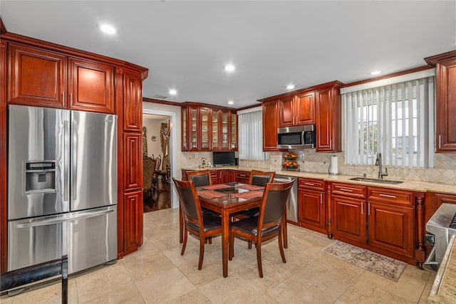 kitchen featuring appliances with stainless steel finishes, backsplash, light stone counters, ornamental molding, and sink