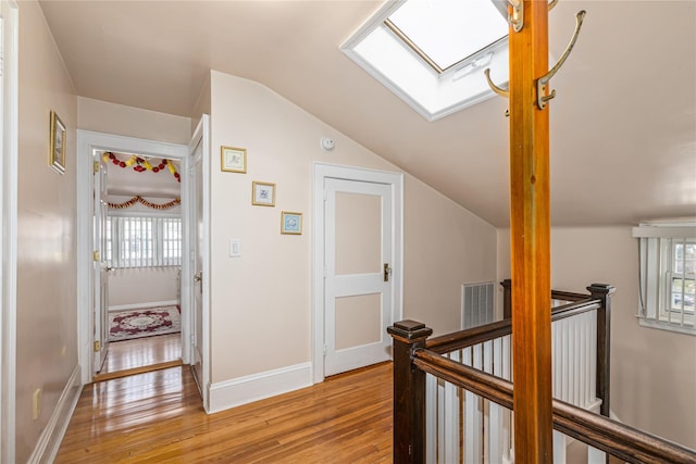 corridor featuring light hardwood / wood-style floors and vaulted ceiling with skylight