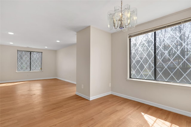 empty room featuring a notable chandelier and light hardwood / wood-style flooring