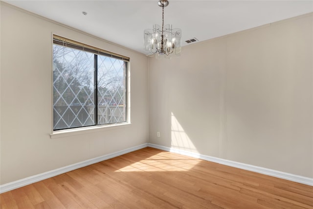 empty room featuring an inviting chandelier and light wood-type flooring