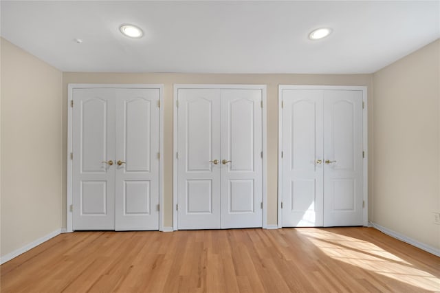 unfurnished bedroom with multiple closets and light hardwood / wood-style flooring