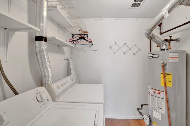 clothes washing area with water heater, independent washer and dryer, and light wood-type flooring