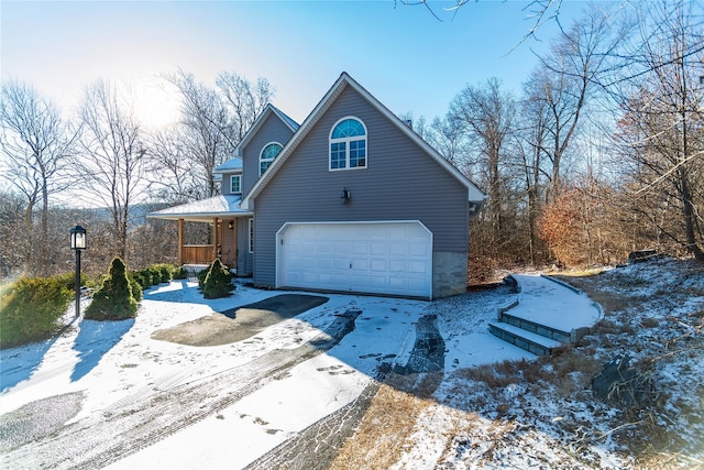 view of snow covered exterior with covered porch and a garage