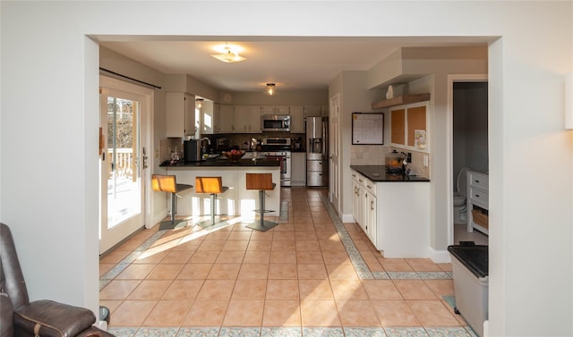 kitchen featuring appliances with stainless steel finishes, backsplash, sink, light tile patterned floors, and a breakfast bar area