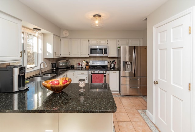 kitchen featuring white cabinets, sink, appliances with stainless steel finishes, light tile patterned flooring, and kitchen peninsula