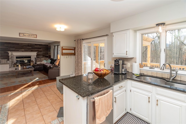 kitchen with dishwasher, light tile patterned floors, white cabinetry, and sink