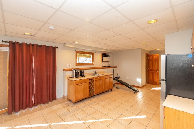 kitchen featuring light tile patterned flooring, stainless steel fridge, a drop ceiling, and sink