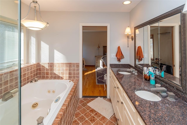 bathroom with tile patterned flooring, vanity, and a relaxing tiled tub