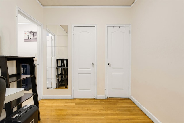 hallway featuring light wood-type flooring and ornamental molding