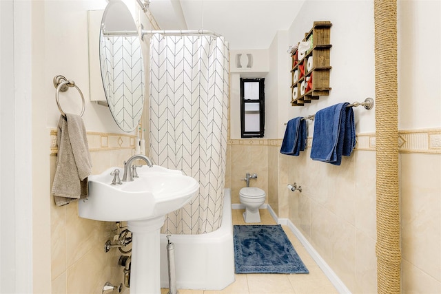 bathroom featuring toilet, a shower with curtain, tile patterned floors, and tile walls