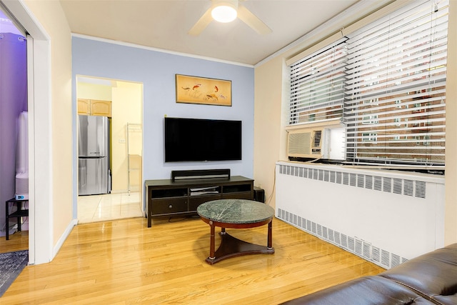 living room with light wood-type flooring, radiator, crown molding, and ceiling fan