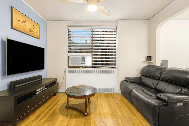 living room with light wood-type flooring, cooling unit, ceiling fan, crown molding, and radiator heating unit