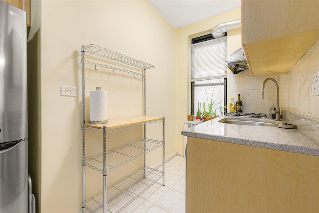 kitchen featuring light tile patterned floors, sink, stainless steel refrigerator, and tasteful backsplash