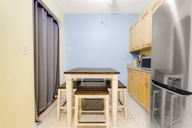 kitchen featuring light tile patterned floors, stainless steel refrigerator, and light brown cabinetry