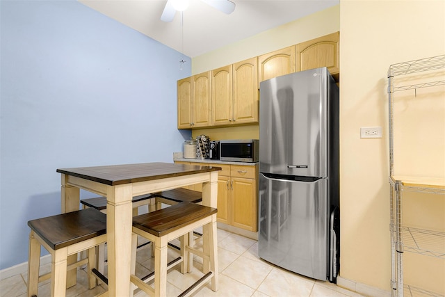 kitchen featuring ceiling fan, light brown cabinets, light tile patterned floors, and stainless steel appliances